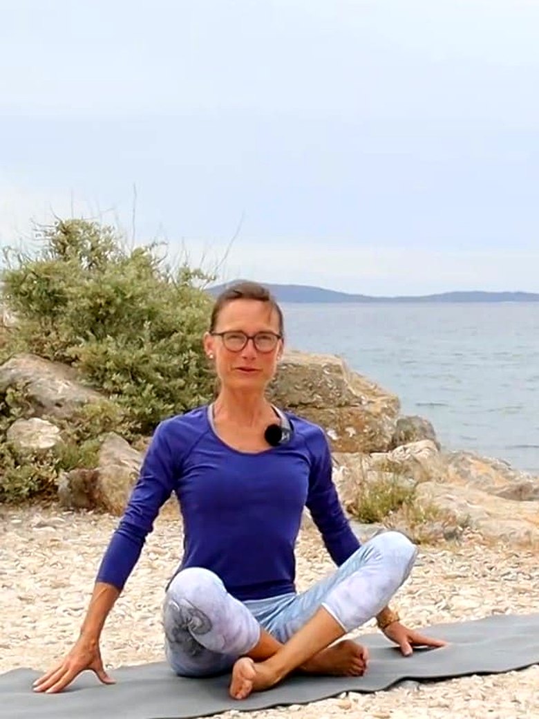Brigitte Gabler sitzt auf ihrer Matte am Meer